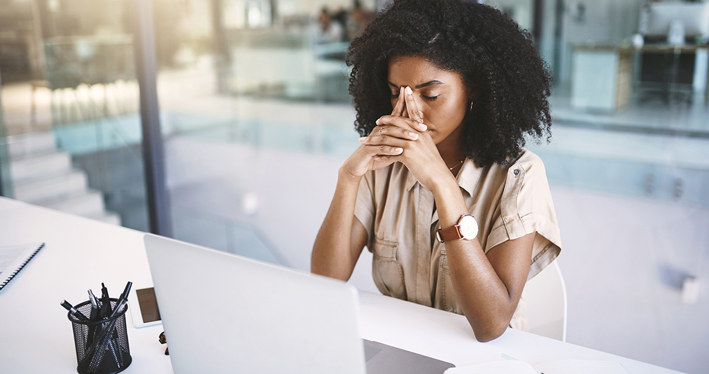 Shot of a young businesswoman looking stressed at her desk in a modern office